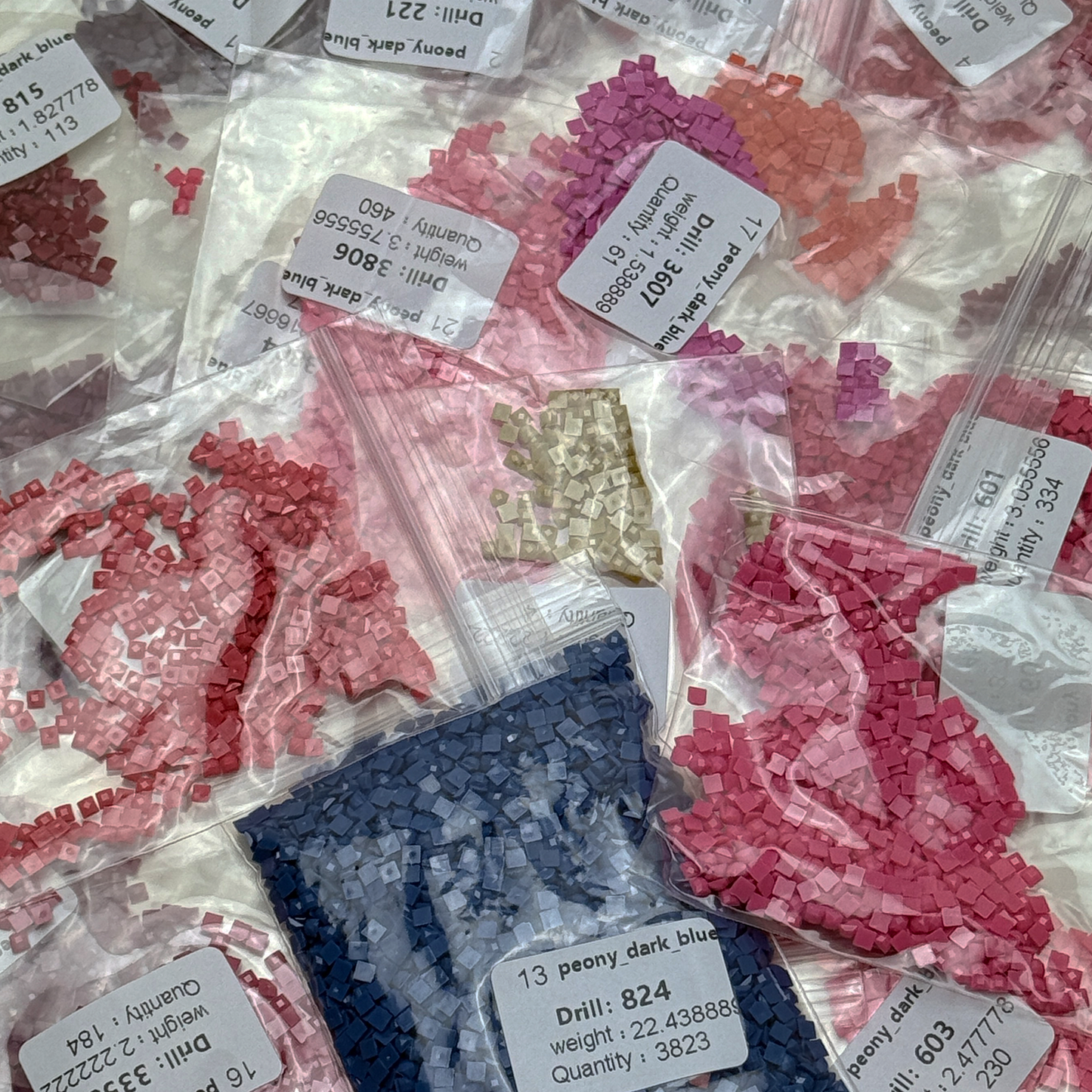 Foto mit Diamond-Painting-Steinchen des Micromosaic Motivs 'peony-darkblue', abgepackt in Zipper-Tütchen und mit Etiketten versehen, auf denen die Farbnummern gekennzeichnet sind.