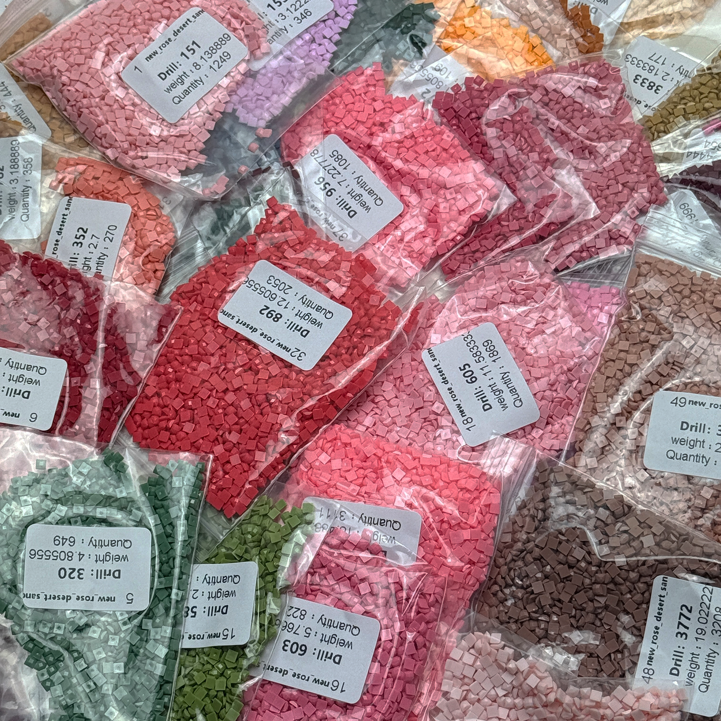 Foto mit Diamond-Painting-Steinchen des Micromosaic Motivs 'rose-desert-sand', abgepackt in Zipper-Tütchen und mit Etiketten versehen, auf denen die Farbnummern gekennzeichnet sind.