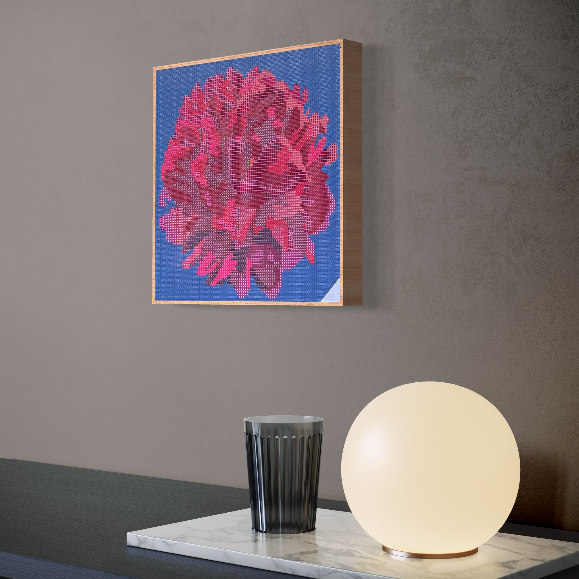 Raumansicht mit Möbeln und Deko-Objekten der Micromosaic-Vorlage 'peony-darkblue' auf stabilem Buchenholzkörper im Format 25x25x3 cm mit einem eleganten,  farblos lackierten Naturholz-Rand. Das Motiv zeigt eine detaillierte Pfingstrosen-Blüte in verschiedenen Rosa- und Rotttönen vor einem monochromdunkelblauen Hintergrund. Inspiriert von Garten-Fotos. Das Kunstwerk enthält insgesamt 22 verschiedene Farbnuancen. Perfekt als stilvolle Wanddekoration oder als exklusives Geschenk für Kreative und Kunstliebhaber