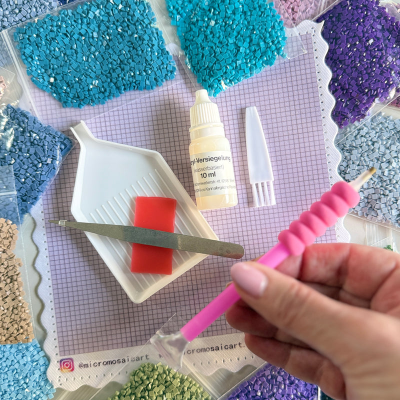 Starter-Kit Freestyle von oben: Freestyle Panel 15 × 15 cm, Steinchen in Beuteln und BASIC TOOL-KIT mit Setzstift und Fingerschoner, Wachs, Schiffchen, Pinzette, Bürstchen und 10 ml Versiegelung